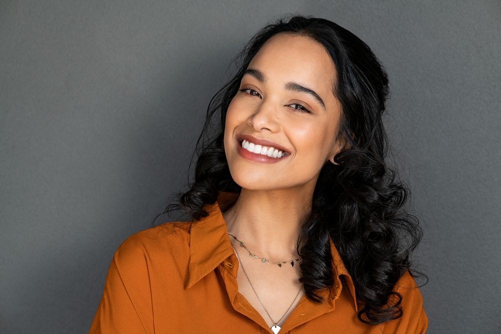 Image of a person holding up two differently priced tooth implants. One is clearly a higher quality, the other looks rusted and old. No text on the image.